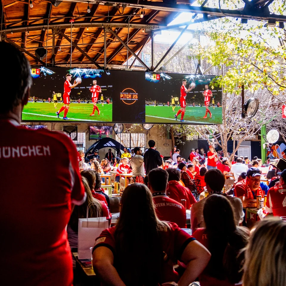 Large LED wall showing soccer at Pitch 25, with guests watching in the bar